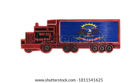 Toy truck with State of North Dakota flag shown isolated on white background. The concept of cargo transportation between countries.