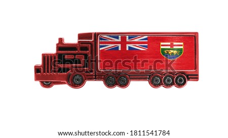 Toy truck with Manitoba flag shown isolated on white background. The concept of cargo transportation between countries.