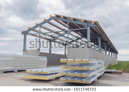 Metal frame of the building with a sandwich panel of insulation on the wall. Construction of a new industrial building. Modern Insulation of the walls of the building panels of insulation. Royalty-Free Stock Photo #1811548192