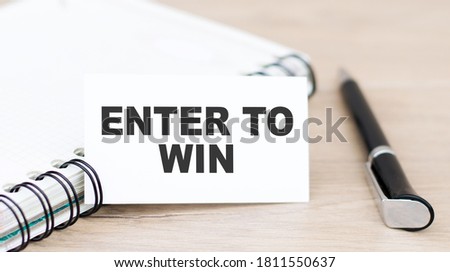 Business concept. Card with text ENTER TO WIN on the table with a notebook and pen