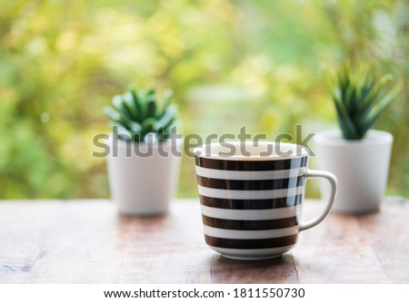 a cup of black coffee on the wooden table in the garden morning under warm soft light in the garden waiting for the falls to come, peacful relaxing time