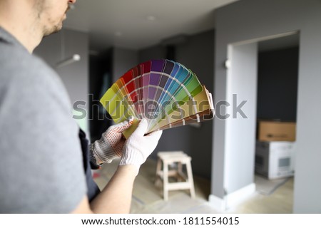 Close-up of palettes samples in hands of handyman. Decorating and designing interior, repainting walls with bright colors. Choice of material, selection of tints Royalty-Free Stock Photo #1811554015