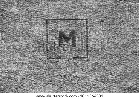 Size M clothing label printed on grey textile background