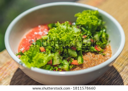 Raw vegan salad with green leaves mix vegetables in white bowl. Cooking recipe blended tomato carrot, parsley cilantro dill greenery cucumber, basil, bell pepper. Healthy food, vitamins for immunity