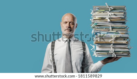 Confident businessman holding a pile of paperwork effortlessly with one hand, easy business administraton concept Royalty-Free Stock Photo #1811589829