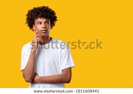 Pensive black teenager. Make decision. Confused yong african guy isolated on orange copy space. Create idea. Social tolerance. Advertising background Royalty-Free Stock Photo #1811608441