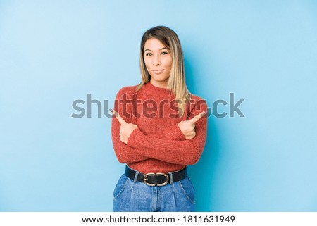 young caucasian woman posing isolated points sideways, is trying to choose between two options.