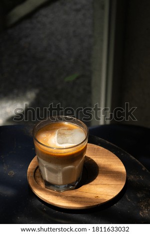 Iced coffee latte in a glass on black table with natural light .