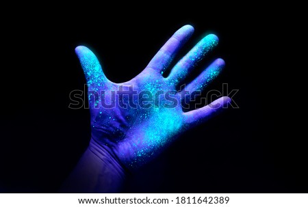 UV Ultraviolet light on a hand illustrating the effect of bacteria and viruses on a surface that has not been washed showing the importance of good hygiene and hand washing. Royalty-Free Stock Photo #1811642389