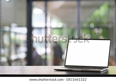 Mock up empty screen laptop on wooden table with space for product display, blurred modern office background.