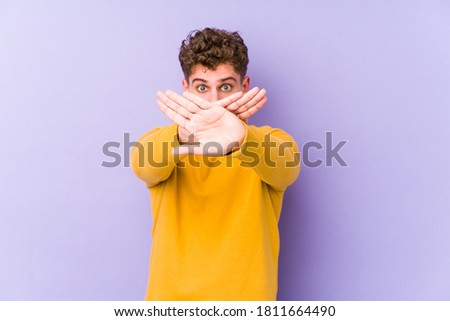 Young blond curly hair caucasian man isolated doing a denial gesture