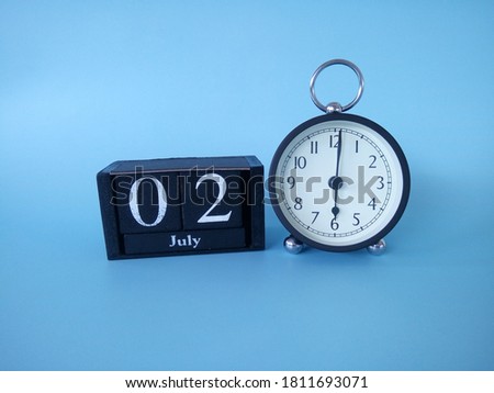 alarm clock isolated on blue background with date July 02