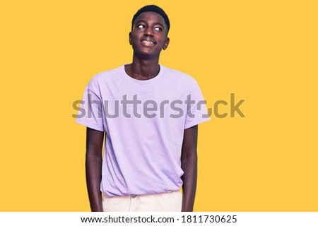 Young african american man wearing casual clothes smiling looking to the side and staring away thinking. 