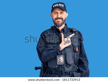 Young handsome man wearing police uniform cheerful with a smile on face pointing with hand and finger up to the side with happy and natural expression 