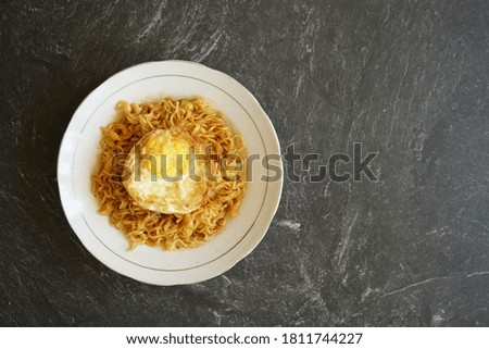 stock photo tasty fried noodle with fried egg on a white plate and a stone pad