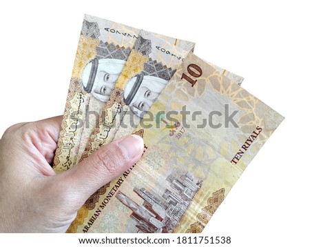 10 Saudi Riyal banknotes in hand isolated on white background.