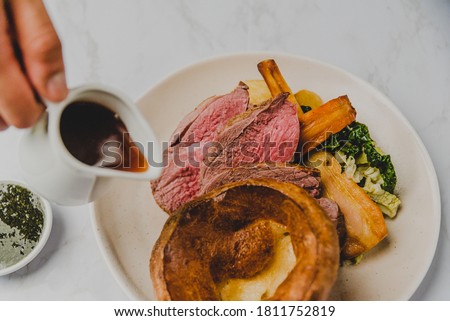 Sunday Roast Beef with Yorkshire Pudding, Roast Potatoes, Carrots, Parsnip, Broccoli and Gravy Royalty-Free Stock Photo #1811752819