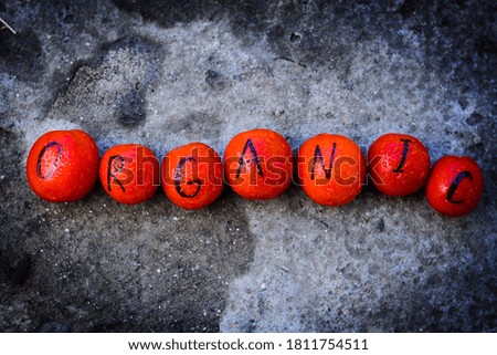 red tomatoes with black organic inscription on them with water drops