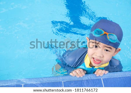 Boy wearing goggles on the edge of the pool. Summer children's sports activity with a parent. Learning and relaxation concept. Just rest after swimming.
