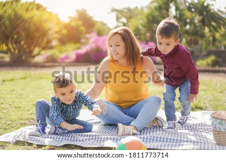 Happy latin mother enjoy day with her twin sons in a nature park - Mother and child love