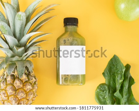 green pastel color drink in plastic bottle container with empty logo label. mixed many vegetables and fruits smoothie juice on studio background. pineapple, green apple, cos decorated.