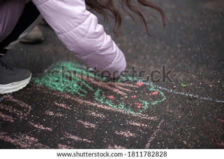 Drawing with chalk on the pavement. The child draws chalk on the road. children's creativity. The girl likes to draw.