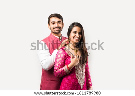 Indian man tying or presenting gold necklace to his beautiful wife on birthday, valentine's day, anniversary or Diwali festival