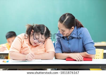 portrait asian disabled child or autism child writing a book and woman teacher helping in classroom Royalty-Free Stock Photo #1811876167