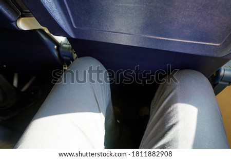 Looking down at narrow leg space in low cost airline seat, knees touching back rest at front Royalty-Free Stock Photo #1811882908