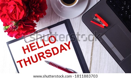 HELLO THURSDAY written in red on white paper near red roses, a computer and a red pen. Motivational concept