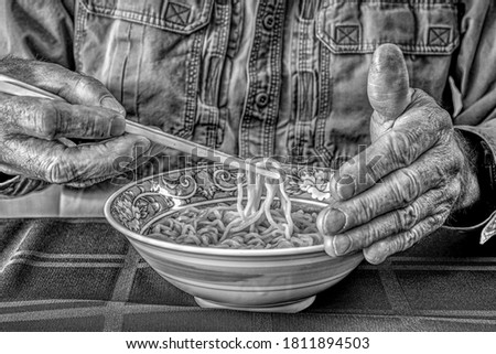 Black and White Horizontal High Dynamic Range (HDR) image of hands and a bowl of noodles with chopsticks