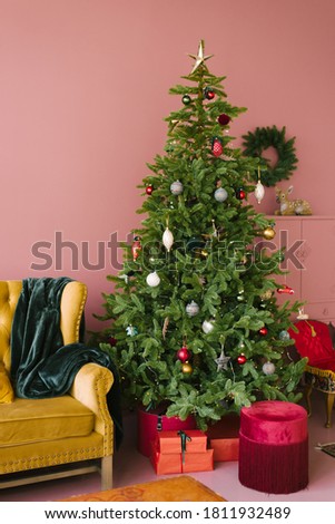 Christmas tree in pink living room style. Vintage yellow sofa with turquoise plaid and maroon velvet banquette. Christmas background.