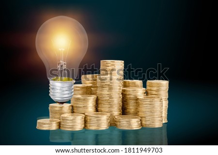 Glowlong light bulb with coins stack on the desk