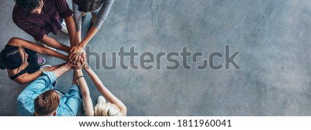 Top view shot of stack of hands. Young college students putting their hands on top of each other symbolizing unity and teamwork. Royalty-Free Stock Photo #1811960041