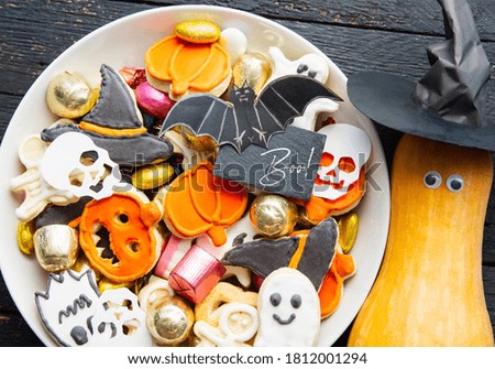 Halloween Jack o Lantern candy bowl with candy and halloween cookies, fresh pumpkin with eyes and witch hat. Trick or Treat on wooden background