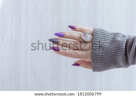 Womans hands with long nails with violet purple nail polish