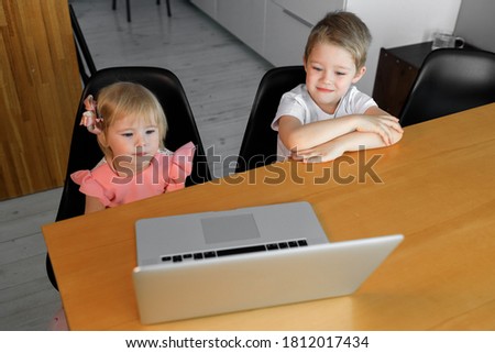 A little boy and a girl watch cartoons on a laptop.