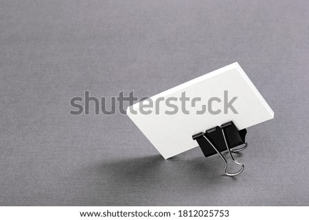 pack of paper blanks for business cards with a metal clip on a light background, isolate
