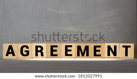 AGREEMENT word on wooden cubes on gray background.