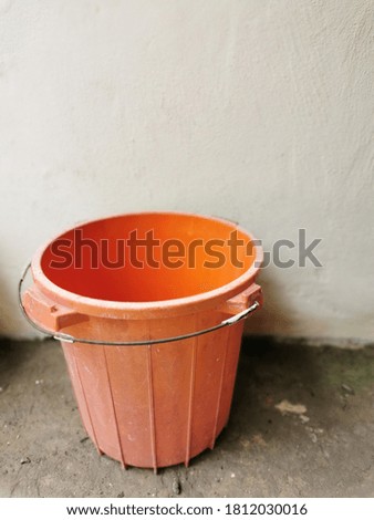 Selective focus on image of old empty plastic bucket on concrete floor.Image may contain noise or grain due to low light.