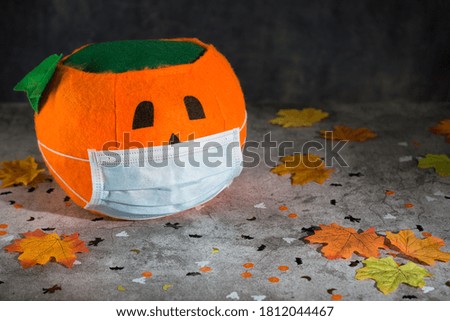 Halloween pumpkin with mask on background decorated with autumn leaves and halloween motifs