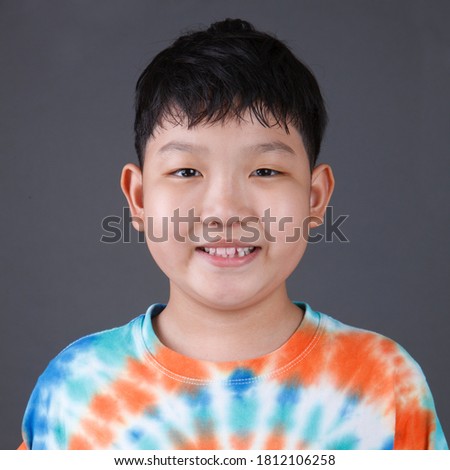 Close up Happy Cute Fat Asian Boy Portrait Wearing Colorful Shirt isolated on Gray Background.
