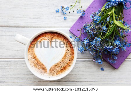 Blue forget-me-not flowers, notebook and a cup of hot coffee.  The concept of holidays and good morning wishes.