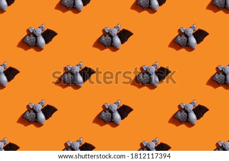  pattern made with marmalade in form of bat on bright orange background. Halloween party concept.