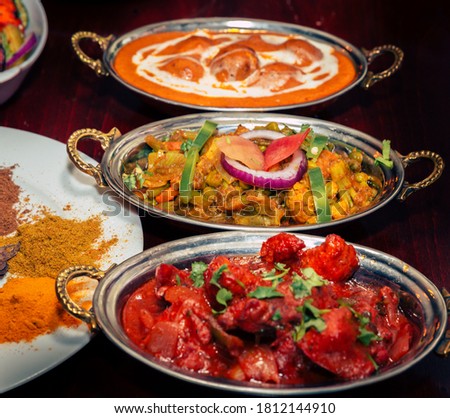 Indian food Curry butter chicken, Palak Paneer, Chiken Tikka, Biryani, Vegetable Curry, Papad, Dal, Palak Sabji, Jira Alu, Rice with Saffron on dark background Royalty-Free Stock Photo #1812144910