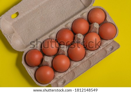 Cardboard package with fresh red eggs on a yellow background. View from above. Diet.