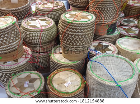 Handmade bamboo container for holding sticky cooked glutinous rice, selling in Thai local marketplace stall. Text on white paper is price.