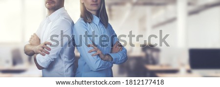 young business people couple posing with arms crossed on office background. copy space