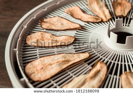 Close-up of dried pear slices placed on plastic tray after dehydration, cooking concept