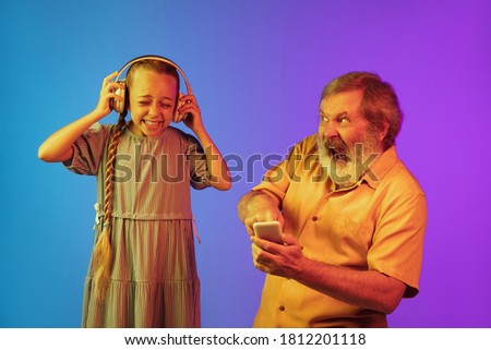 Senior man and granddaughter on neon background